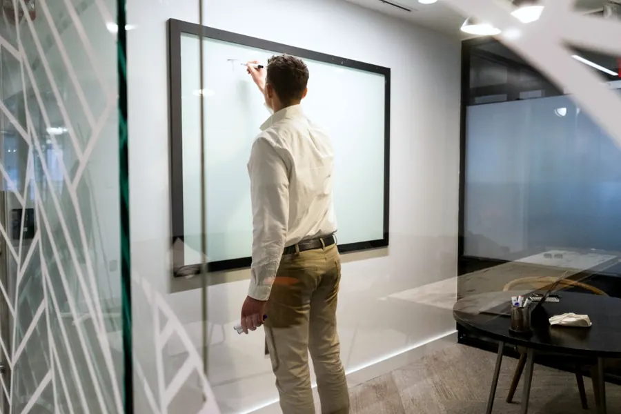 A strategy session at a glass writing wall in a modern office