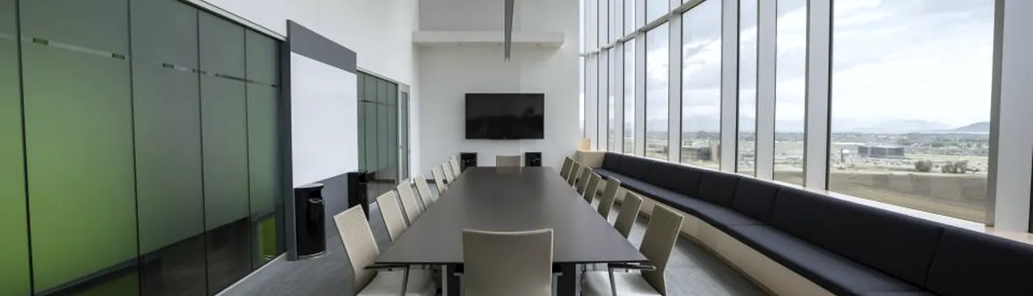 A long meeting table beside a window wall
